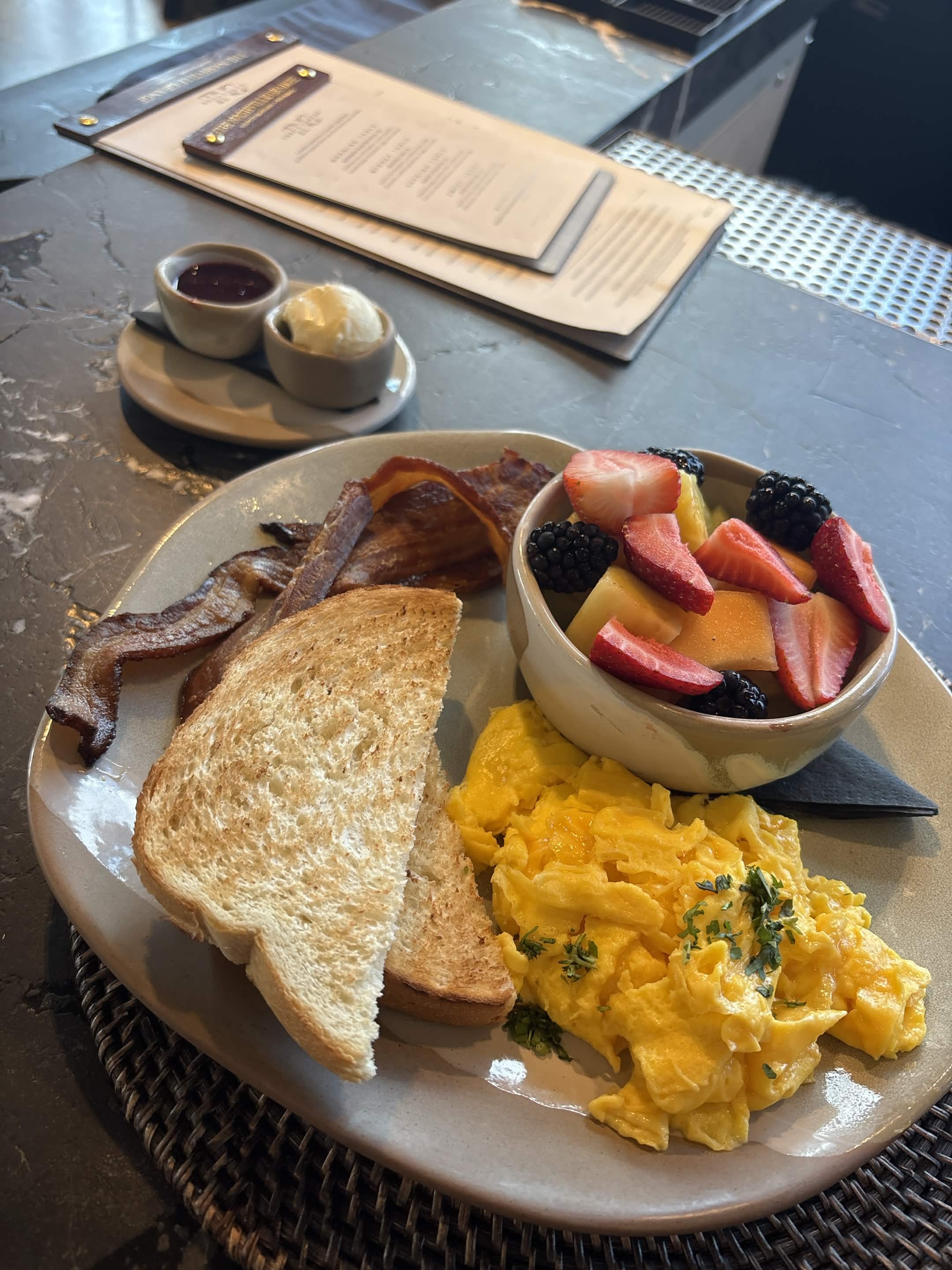 Scrambled eggs toast bacon fruit